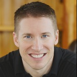 Jesse Mecham photographed in a dark shirt and inside a room, smiling