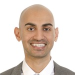 Passport snap of Neil Patel wearing a suit and smiling broadly