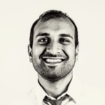 Black and white passport picture of Sujan Patel in a broad smile